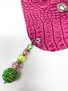 pink crocodile skin textured drink cover with green and pink beads lying flat