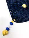 deep, navy blue drink cover with crocodile skin texture from the top view with a gold circlet for a straw hole