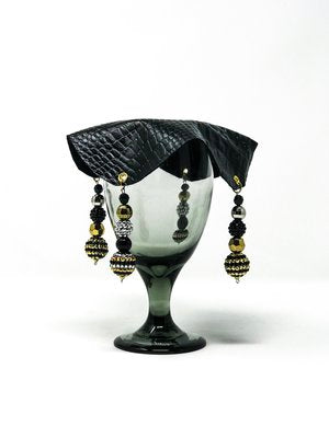 black crocodile skin textured drink cover with white and crimson beads on glass,